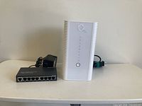 Front view of Hitron modem standing beside Asante hub and power supply
