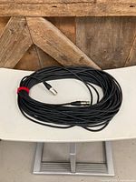 Coiled 100-ft XLR cable on chair, both connectors visible