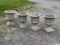 Four matching garden urns side by side on gravel