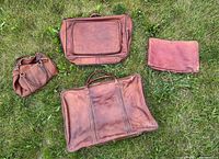 All four leather travel pieces laid out on grass