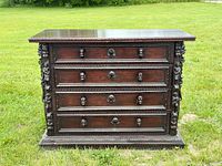 front view showing four drawers with mask pulls and carved details
