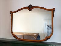 Full view of mirror on wall showing frame shape and carvings
