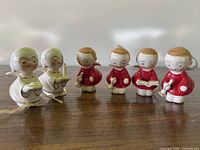 Front view of six ceramic angel ornaments showing colors, poses, and condition