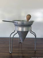 Full view of assembled aluminum conical strainer on stand with pestle inside