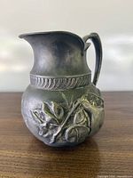 Front view showing pear relief, handle, spout