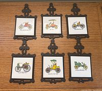 Full view of six cast iron framed car tiles on wall