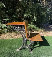 Right side view showing ornate cast iron frame and maple seat/back