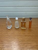 Front view of all four miniature perfume bottles standing in a row