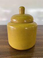 Front view of yellow wooden canister with lid