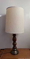 Full view of one lamp showing wood column, brass base, drum shade