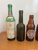 Group of Nozzole wine, plain green, and Goebel Beer bottles