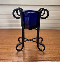 Full view of cobalt blue glass vase in wrought iron stand