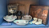 Full shelf view showing copper plaque, plates, bowls, vases, figurines, frames