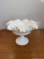 Side view of Fenton Silver Crest milk glass pedestal compote showing ruffled clear edge and pedestal base