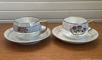 Two teacups with matching saucers showing overall condition and designs