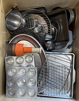 Drawer filled with assorted metal bakeware, cooling racks, basting brush visible