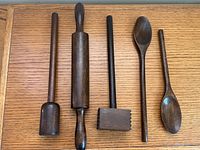 Five dark wooden utensils laid side by side on wood surface