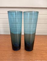Front view of both tapered emerald green glass vessels standing side by side