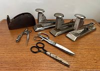 Group view of staplers, tape dispenser, scissors, compass, and staple remover