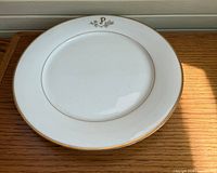 Top view of white platter showing gold rim and monogram