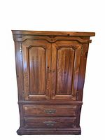Front view of pine armoire dresser showing doors, drawers, hardware, and carved details