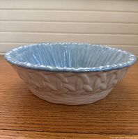 Side view of stoneware bowl showing basket weave exterior pattern and cream glaze