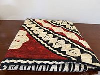 Folded fabric showing red, black and cream tribal pattern