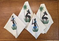 All four napkins folded showing painted designs