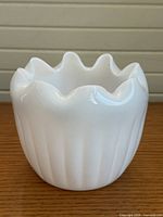 Front view of white milk glass ribbed rose bowl vase showing ribbed sides and ruffled rim