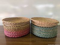 Two stacks of wicker plate holders showing pink and teal accented rims