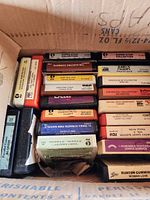 Box of assorted 8-track tapes, multiple colors and labels visible