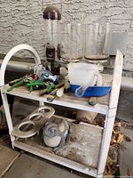 Shelf with garden tools, glass vases, lantern/bird feeder, frog statue, metal stand, hooks and stakes