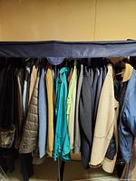 Full rack of assorted jackets and coats with wardrobe cover