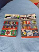 Two sealed DMC craft thread packs on surface