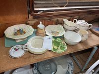 Group view of all ceramic pieces and glass stand on shelf