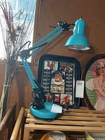 Full view of turquoise adjustable desk lamp on wooden surface