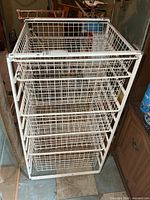 Front angled view of full cabinet showing five baskets and white metal frame