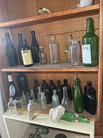 Shelved assortment of green, brown, aqua and clear bottles