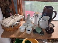 Shelf view showing pitchers, vases, cups, plaque, flower frogs
