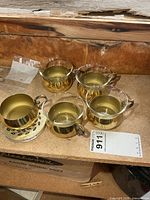 five metal holders and four glass inserts on shelf