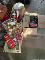 assorted Christmas décor on bench: ornaments box, gold apples bag, cookie cutter box, lights in carton