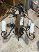 Full view of chandelier showing wood post, four metal arms, candle sockets