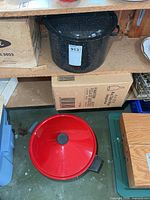 Shelf with black speckled enamel canner and red-lidded electric wok