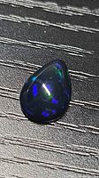 Front view of pear-shaped Ethiopian black opal showing blue and green flashes