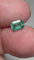 Front view of octagon-cut emerald held between fingers