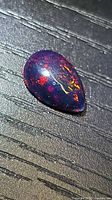 Pear cabochon black opal showing red and purple flashes