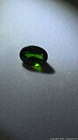 Front view of loose green oval gemstone on neutral background