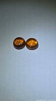 Two matched orange cabochon garnets on neutral background