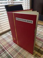 closed red hardcover world stock book showing cover and edge wear