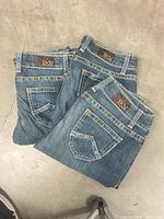 Back view folded jeans showing DoV leather patches and pocket stitching